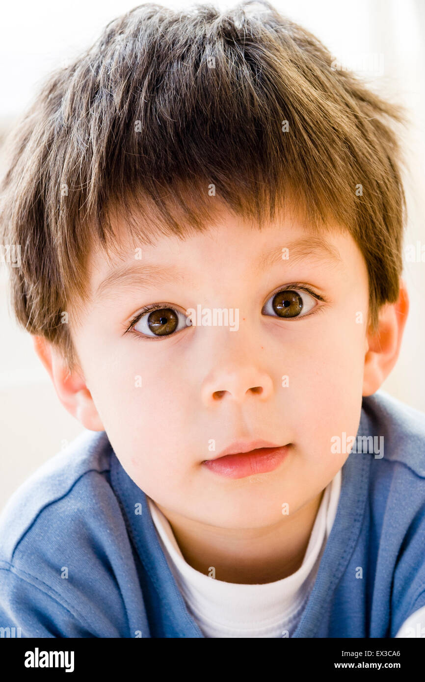 Bambino caucasico, boy, 5-6 anno vecchio, della testa e della spalla, la faccia rivolta verso il visualizzatore. Guardando con delicata felice espressione sul suo volto. Foto Stock