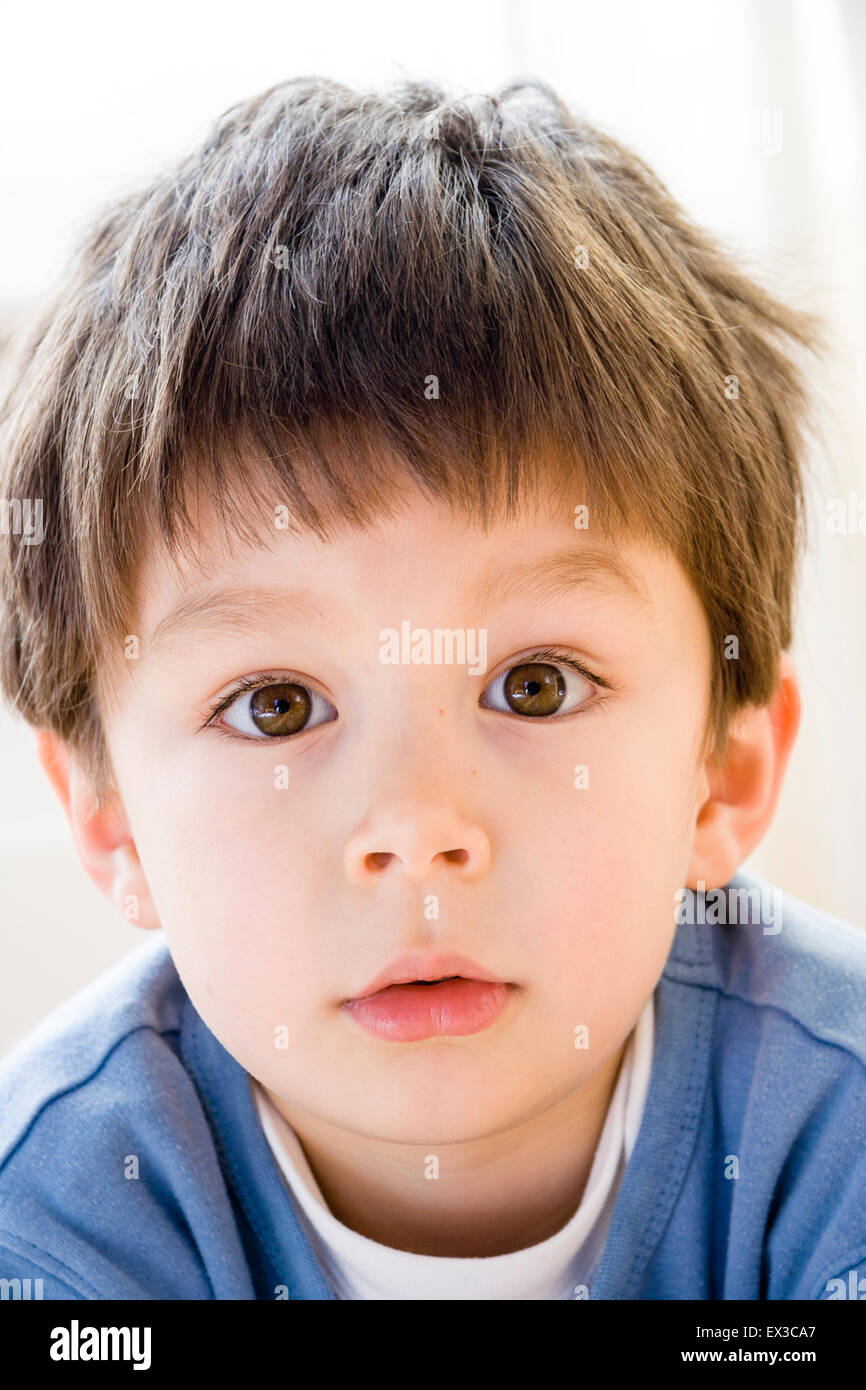 Bambino caucasico, boy, 5-6 anno vecchio, della testa e della spalla, la faccia rivolta verso il visualizzatore. Guardando con sconcerto e espressioni di sorpresa sul suo volto. Foto Stock