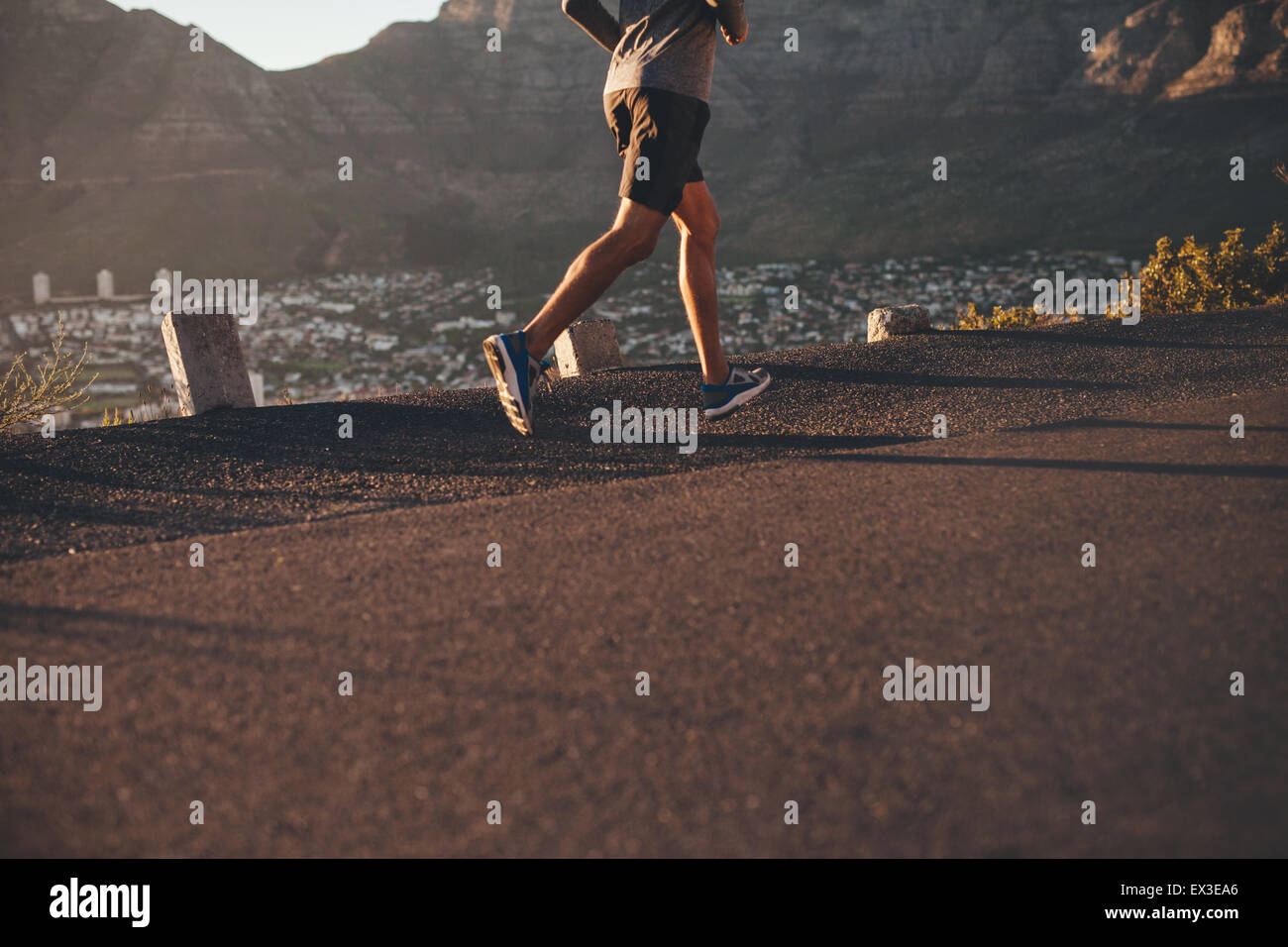 Sezione bassa immagine del giovane uomo che corre sulla strada di campagna in mattina. Focus su atleta maschio gambe. Foto Stock