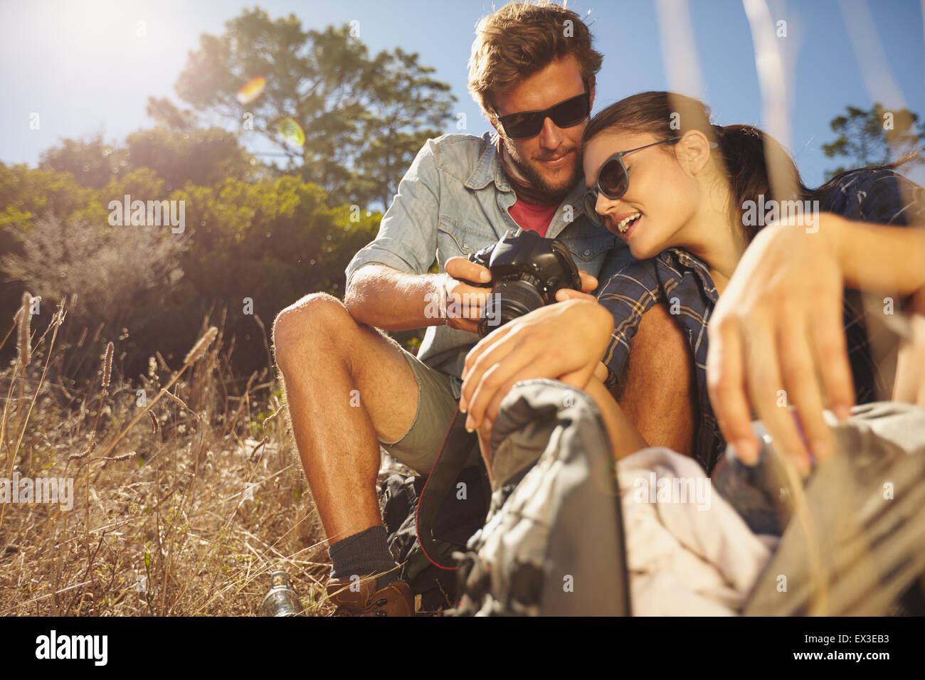 Colpo all'aperto di un escursionista giovane guardando la fotocamera su una giornata d'estate. Uomo caucasico e donna su escursioni di viaggio prendendo una pausa sit Foto Stock