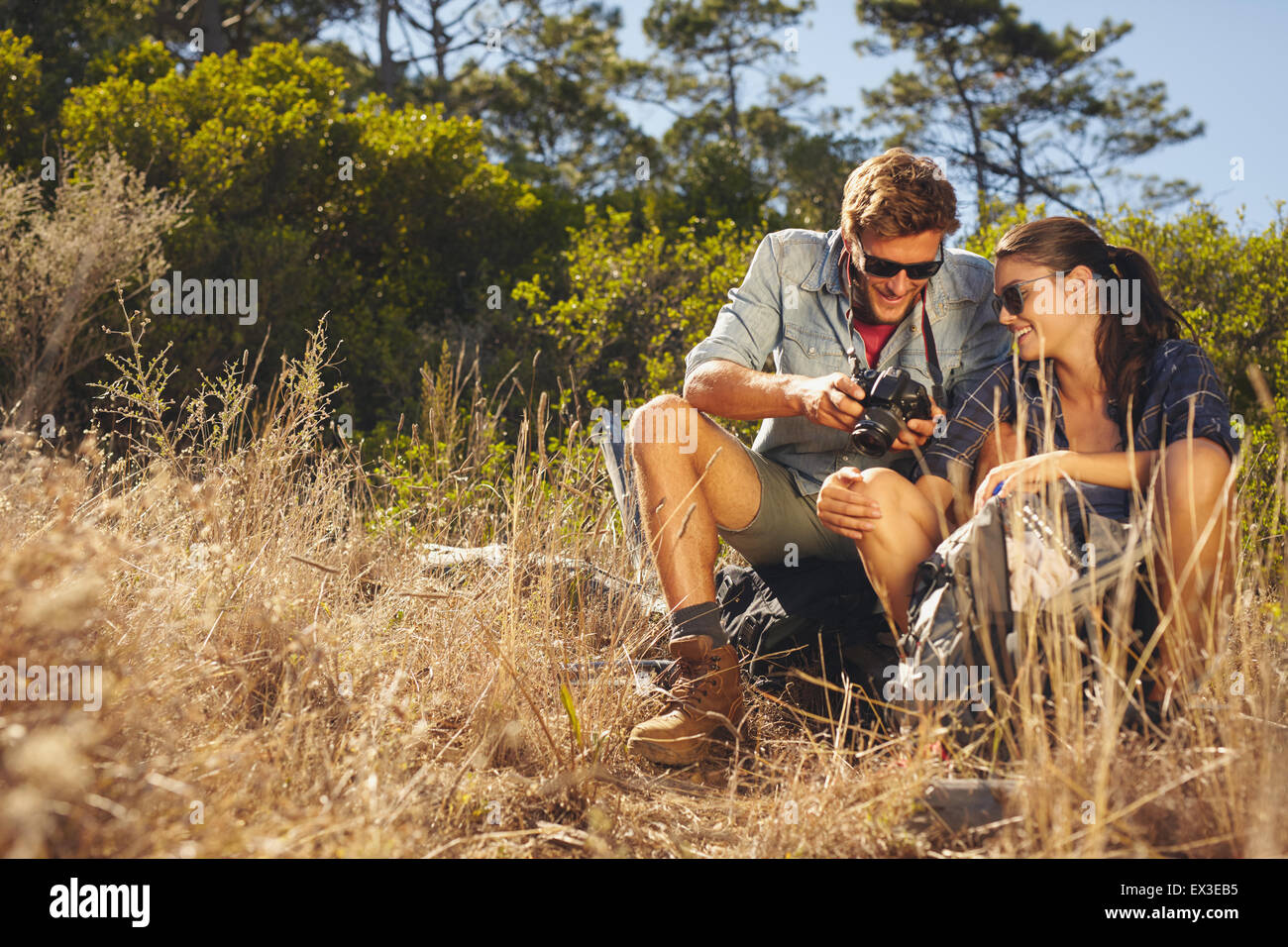 Coppia giovane all'esterno guardando le foto sulla fotocamera. Uomo caucasico e donna su escursioni di viaggio prendendo una pausa. Foto Stock
