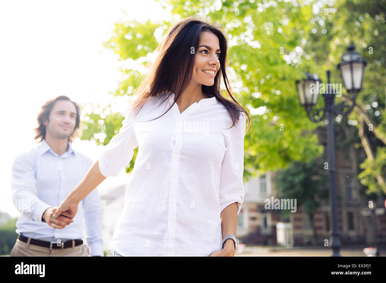 Donna felice azienda mano d'uomo e lo conduce all'aperto Foto Stock
