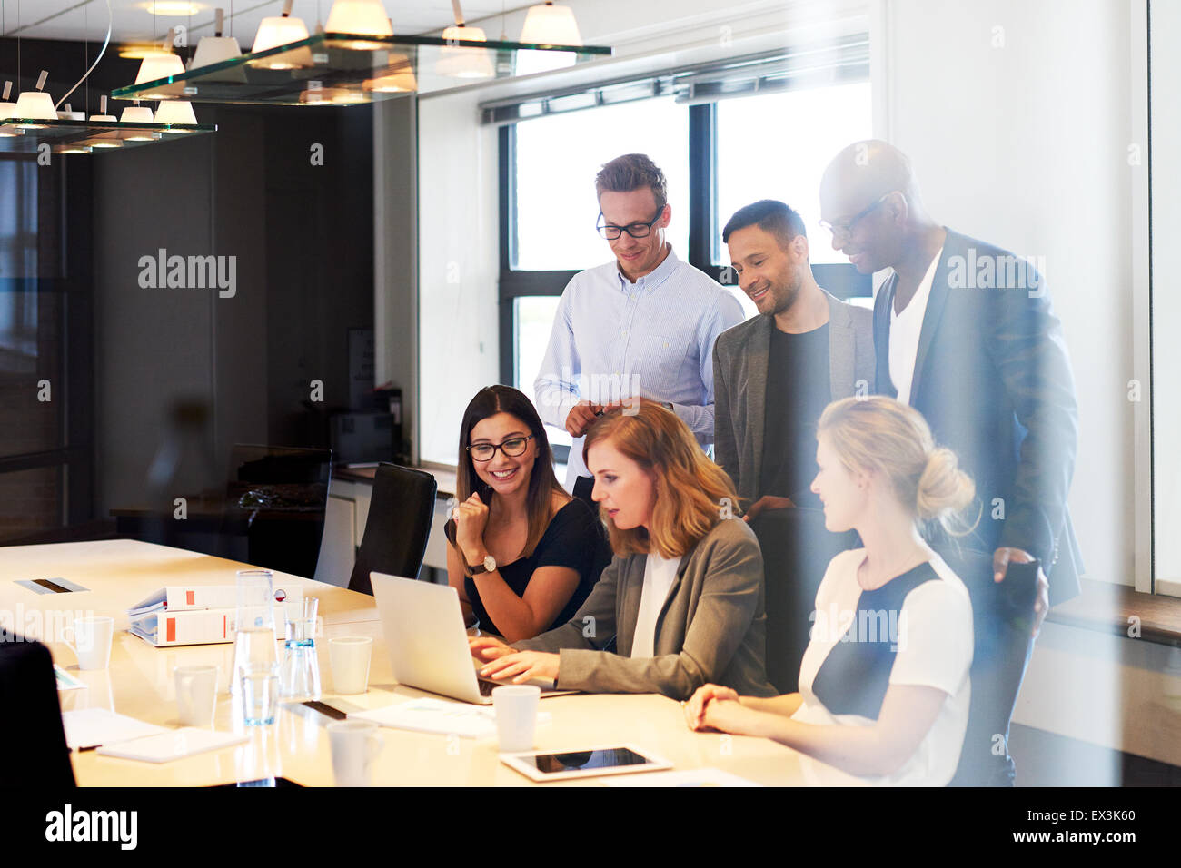 Un gruppo di giovani dirigenti in sala conferenze si sono riuniti insieme guardando al laptop Foto Stock
