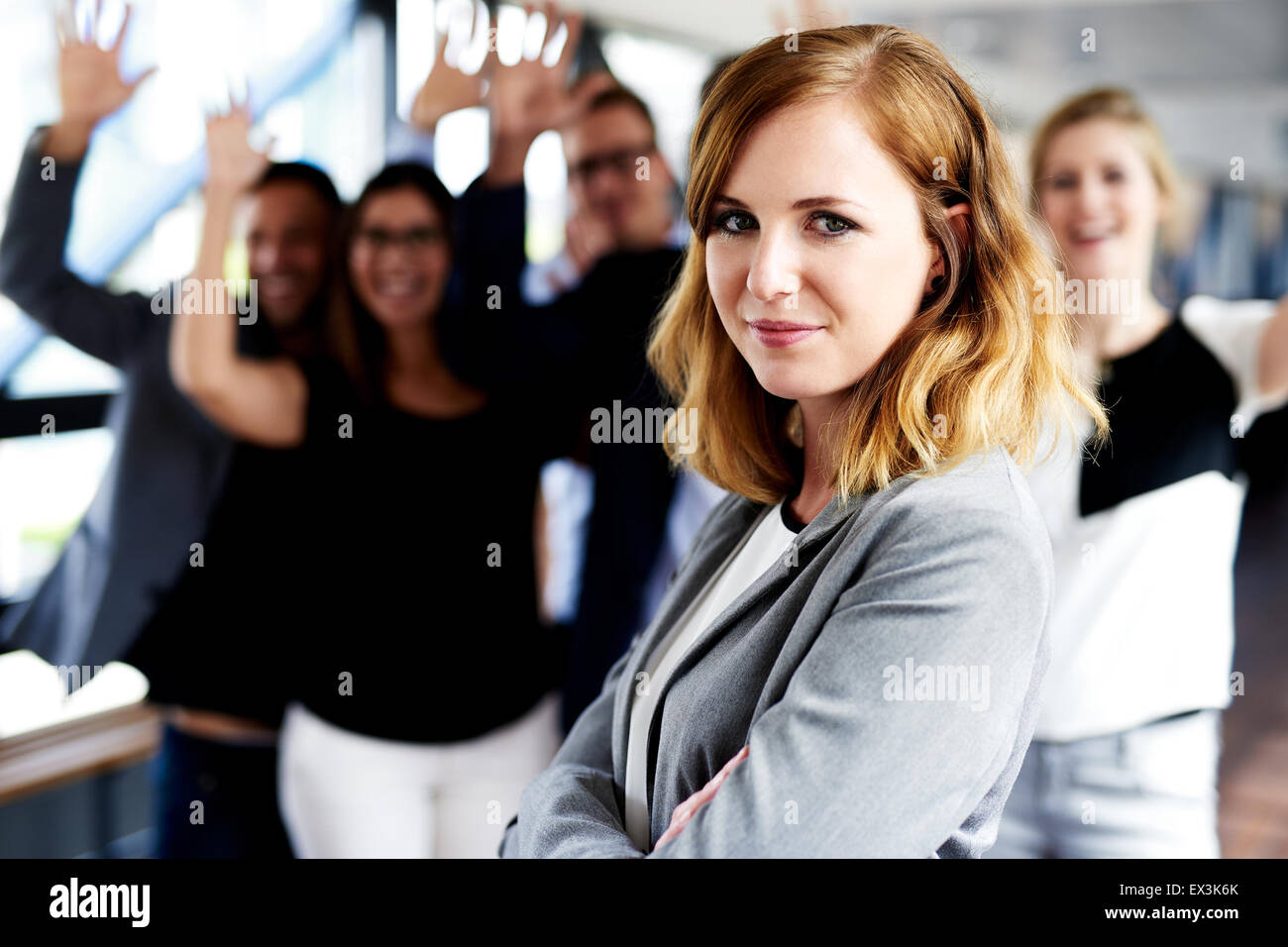 Femmina bianca executive in piedi di fronte ai colleghi con le braccia in aria Foto Stock