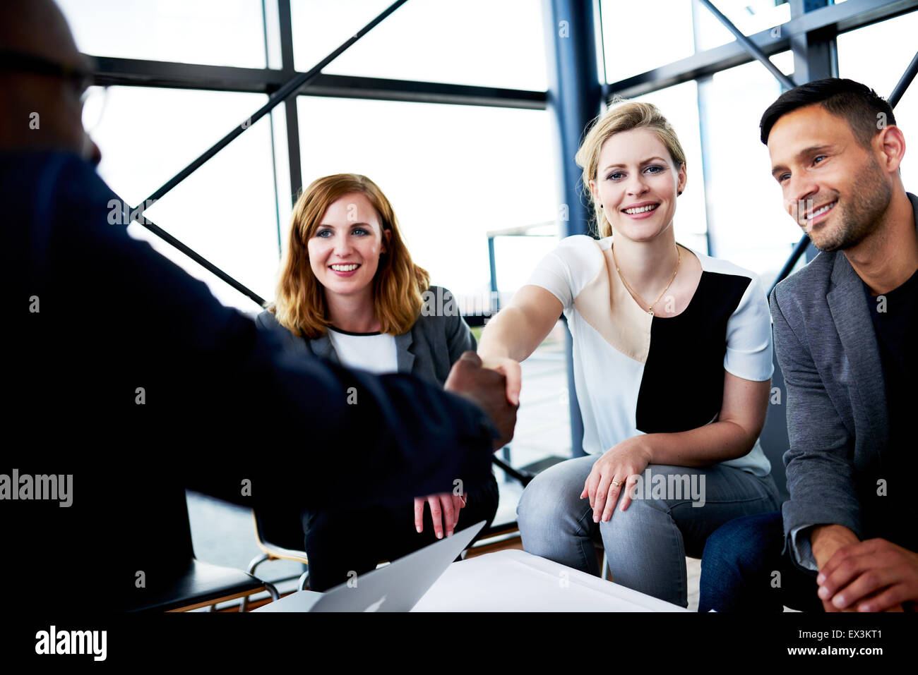 Femmina bianca di scuotimento executive collega la mano e sorridente in telecamera Foto Stock