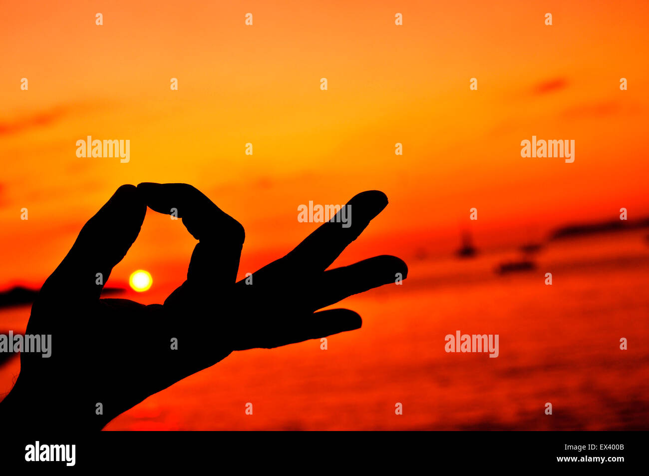Primo piano di un giovane uomo meditando con le sue mani in gyan mudra al tramonto Foto Stock