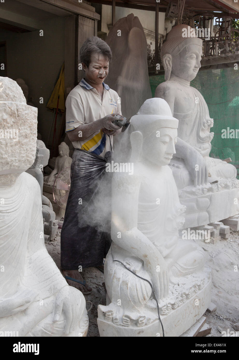 Intagliatore di marmo utilizza power tool a scolpire la statua di Buddha con nessuna protezione contro la polvere e senza una protezione per gli occhi Foto Stock