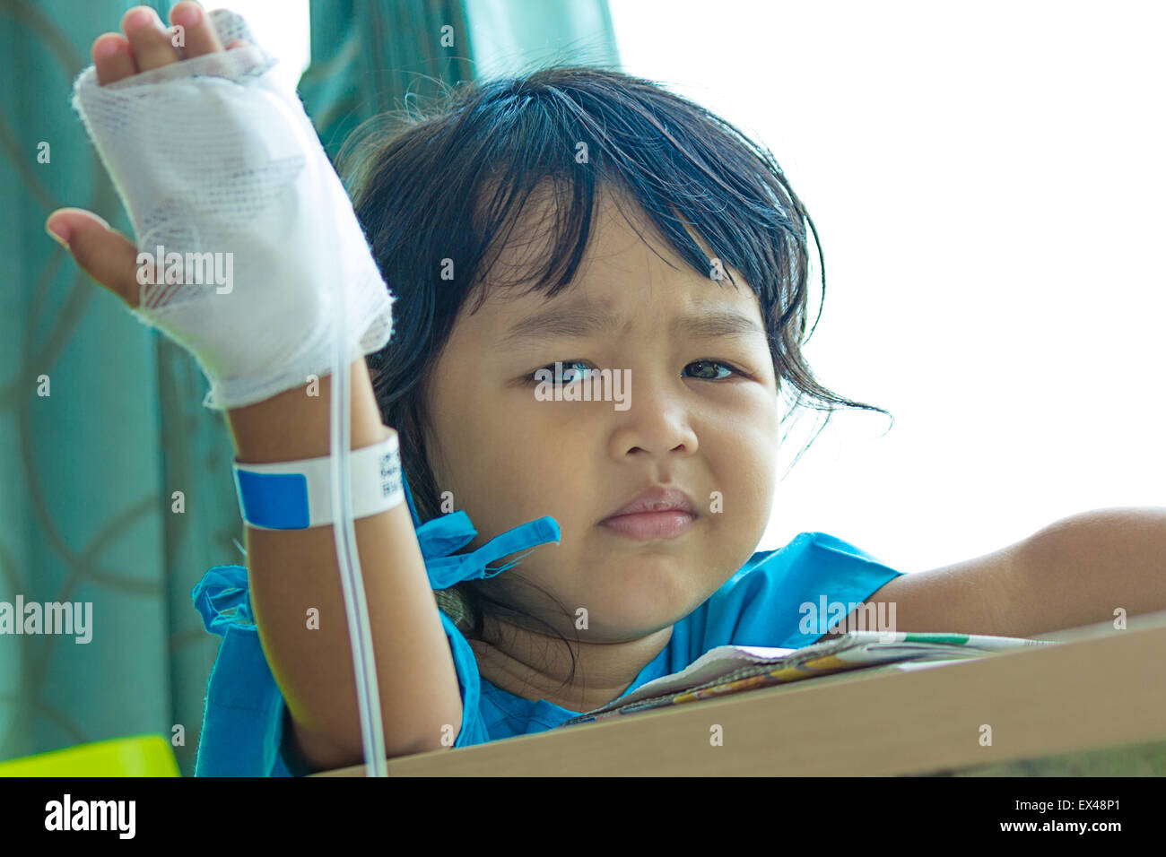 Malattia bambini asiatici gridare, seduto su una sedia in ospedale, soluzione salina per via intravenosa (IV) a portata di mano Foto Stock
