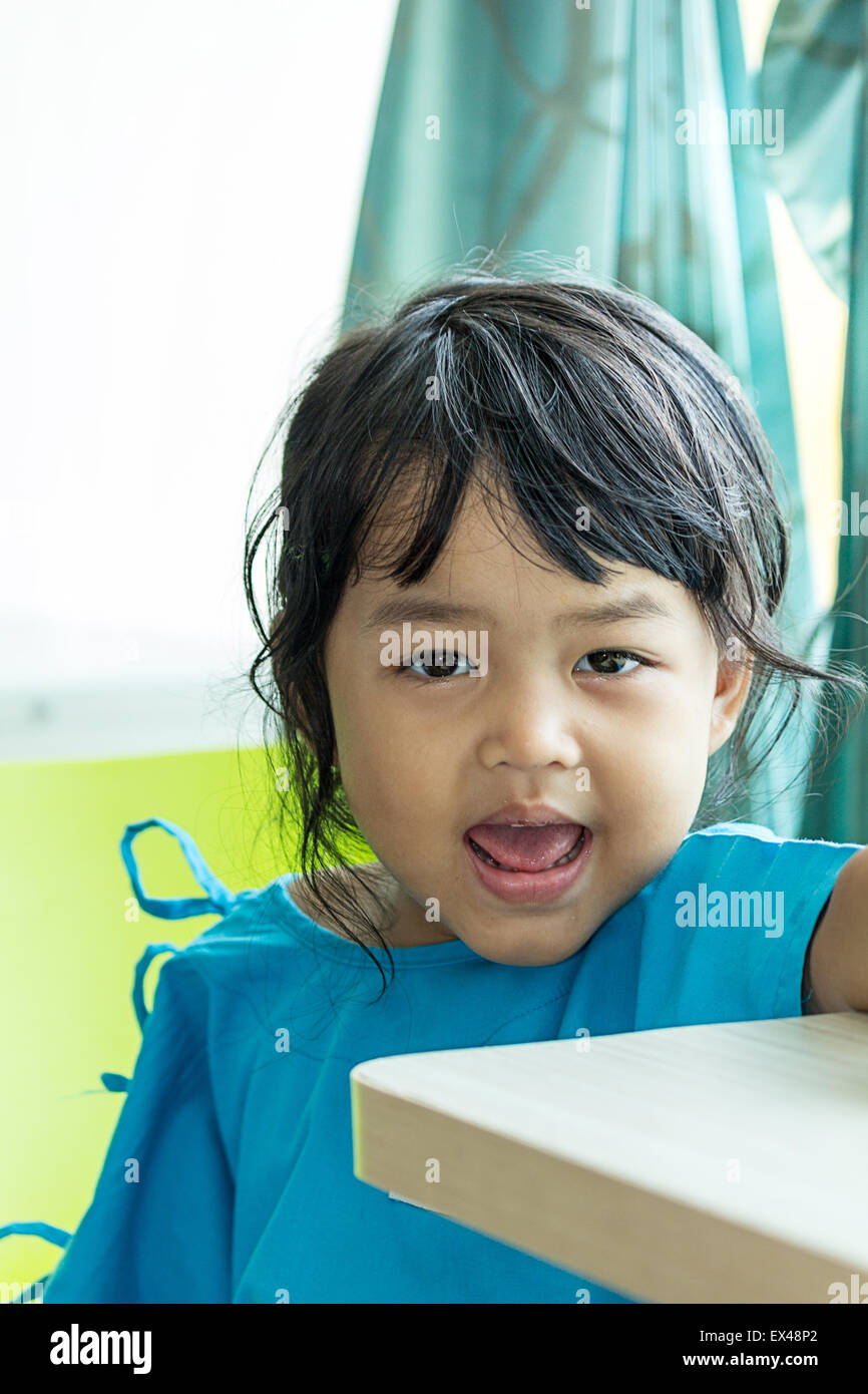 Malattia poco ragazzi asiatici seduto su una sedia in ospedale, soluzione salina per via intravenosa (IV) a portata di mano Foto Stock