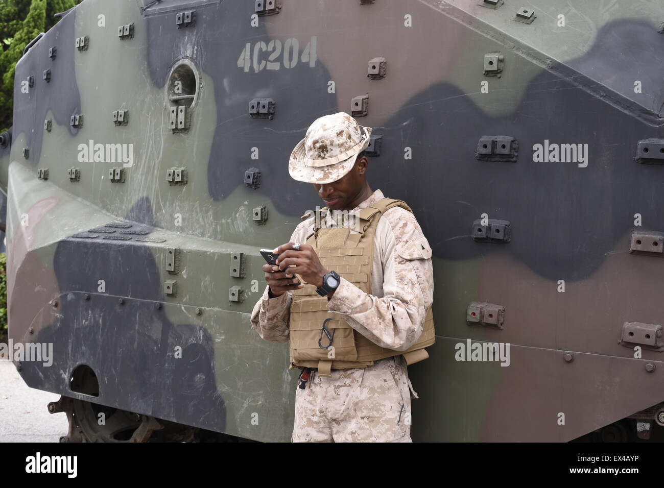 Soldato dell'esercito sul suo telefono cellulare nella parte anteriore di un serbatoio Foto Stock