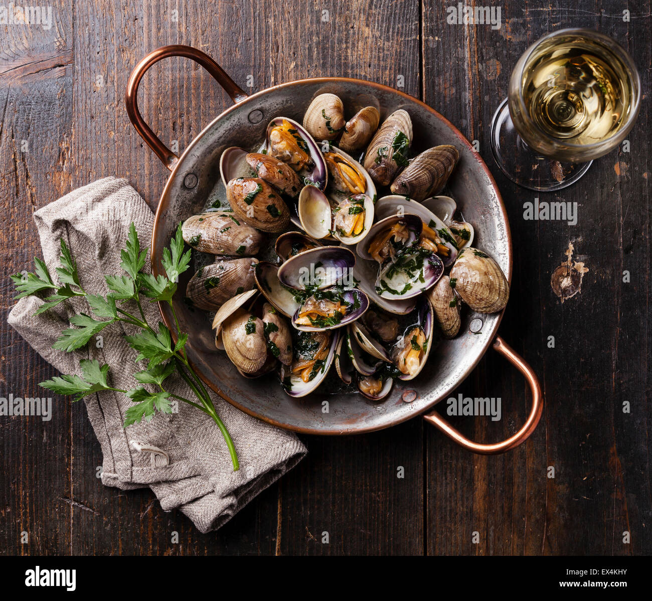 Gusci vongole le vongole con il prezzemolo in rame piatto di cottura su scuro dello sfondo in legno Foto Stock