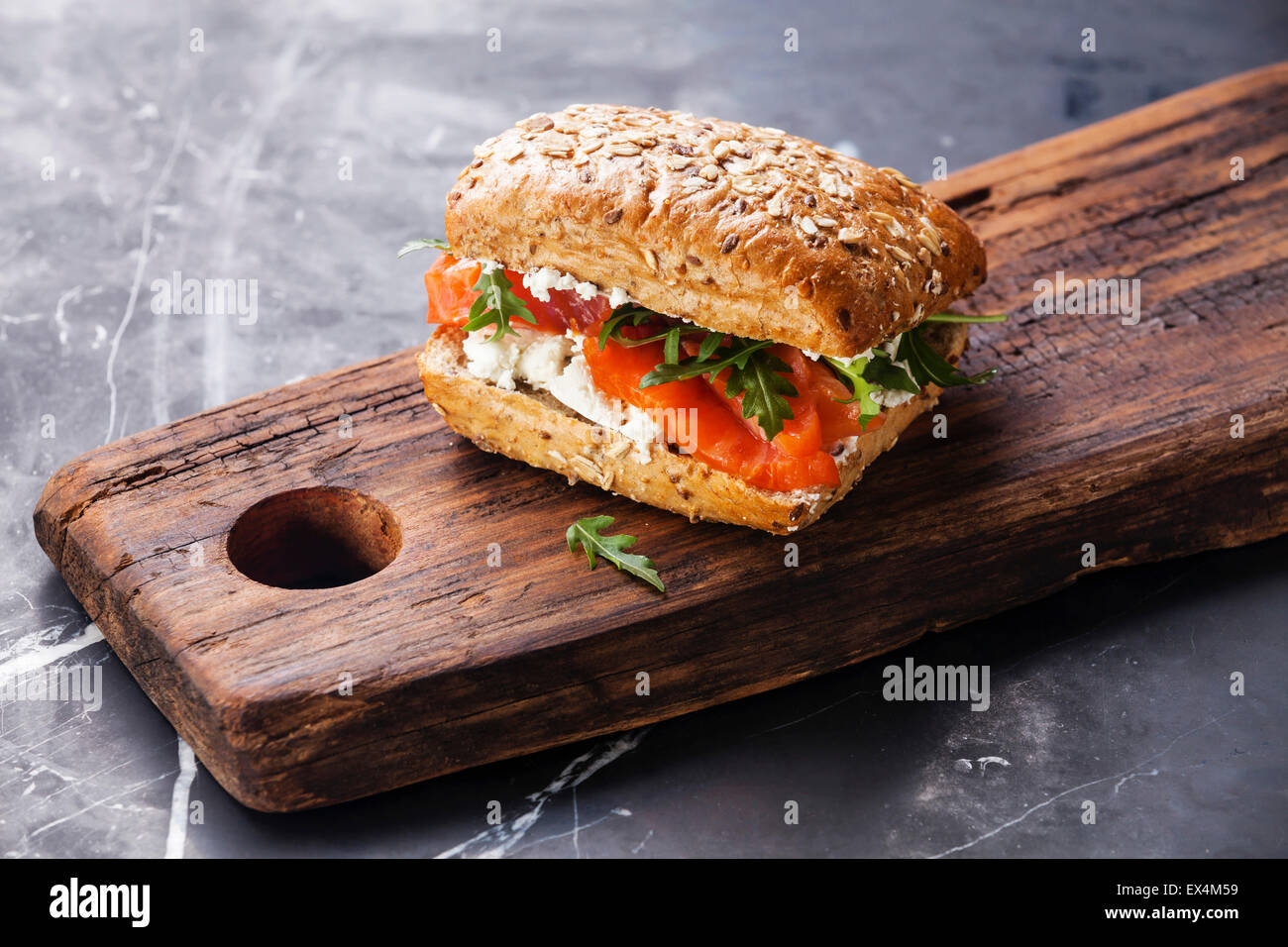 Sandwich di pane ai cereali e salmone scuro su sfondo marmo Foto Stock