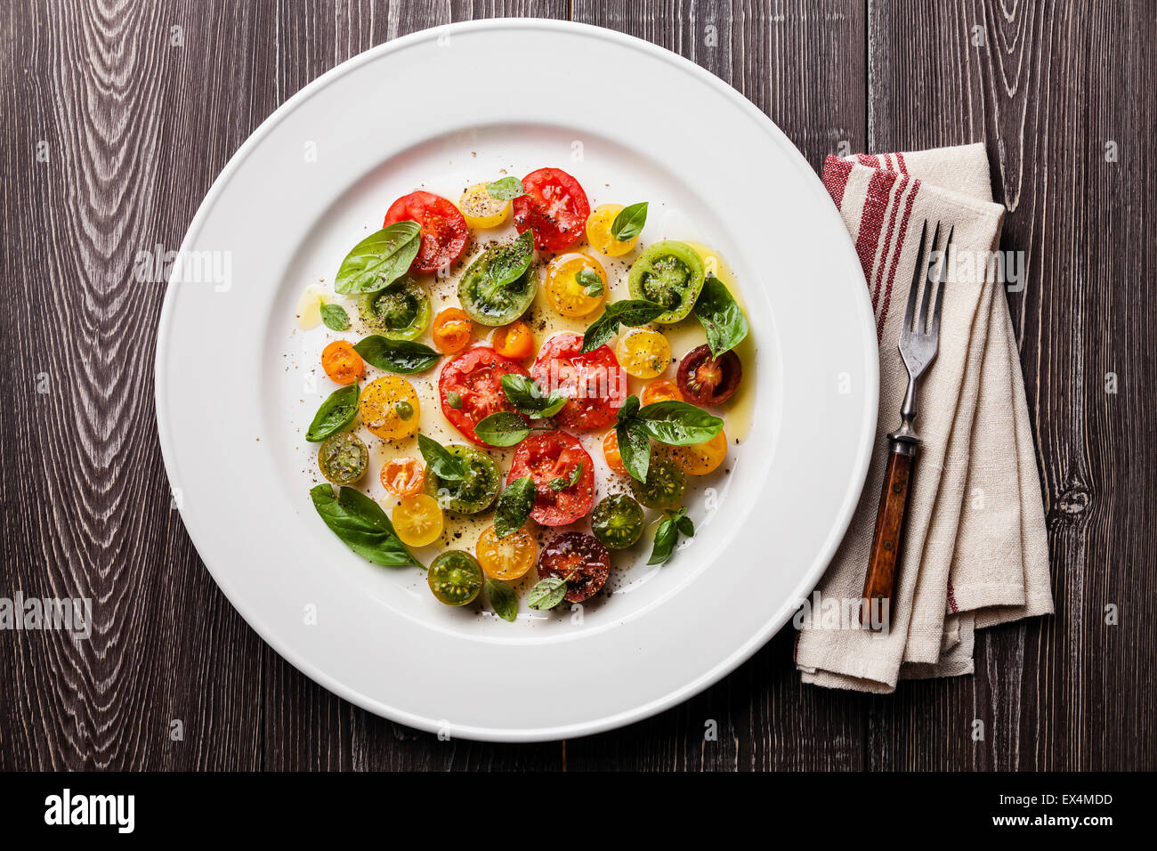 Mature colorato fresca insalata di pomodori con basilico e olio d'oliva sul grigio Sfondo di legno Foto Stock