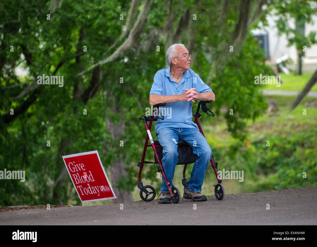 Uomo anziano si siede sul suo walker da una donazione di sangue segno in Pioneer Days Festival in North Florida cittadina di molle di alta. Foto Stock