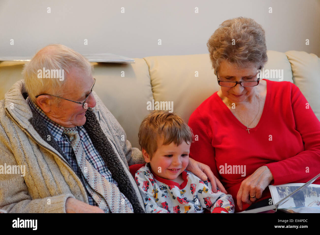 Un bambino (3 anni) in pigiama avente una storia prima di addormentarsi con i suoi nonni Foto Stock