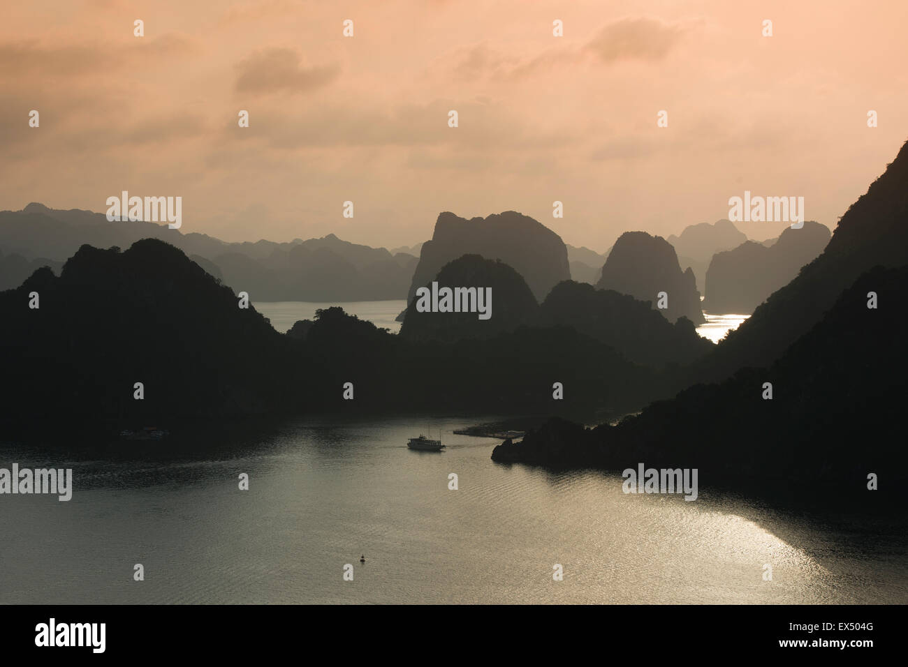 Barca in acqua al tramonto nella Baia di Ha Long o Vinh Ha Long, scogliere calcaree, Sito Patrimonio Mondiale dell'UNESCO, Golfo del Tonchino Foto Stock