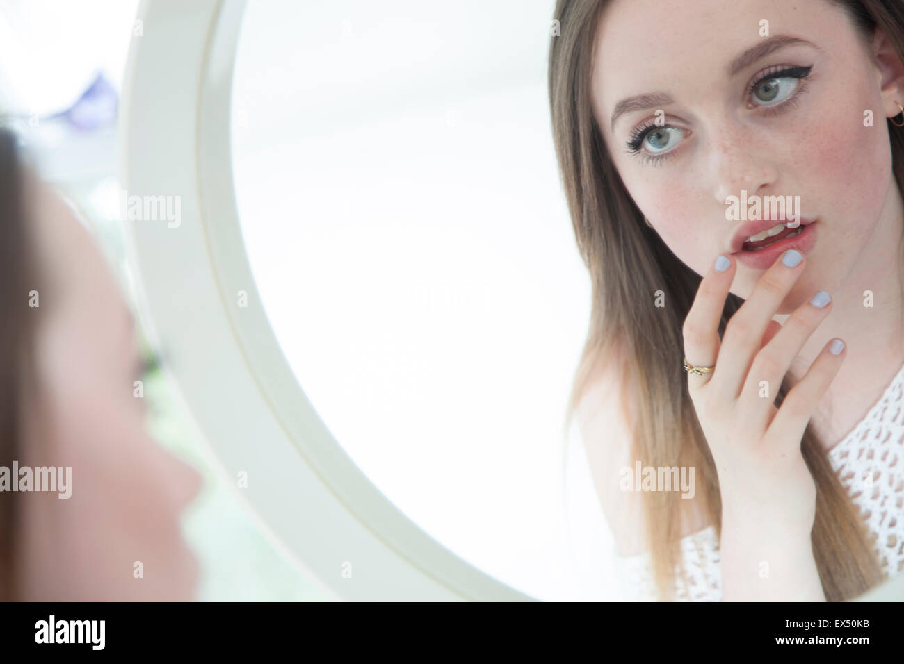 Ragazza adolescente cercando in Mirror di toccare le sue labbra Foto Stock