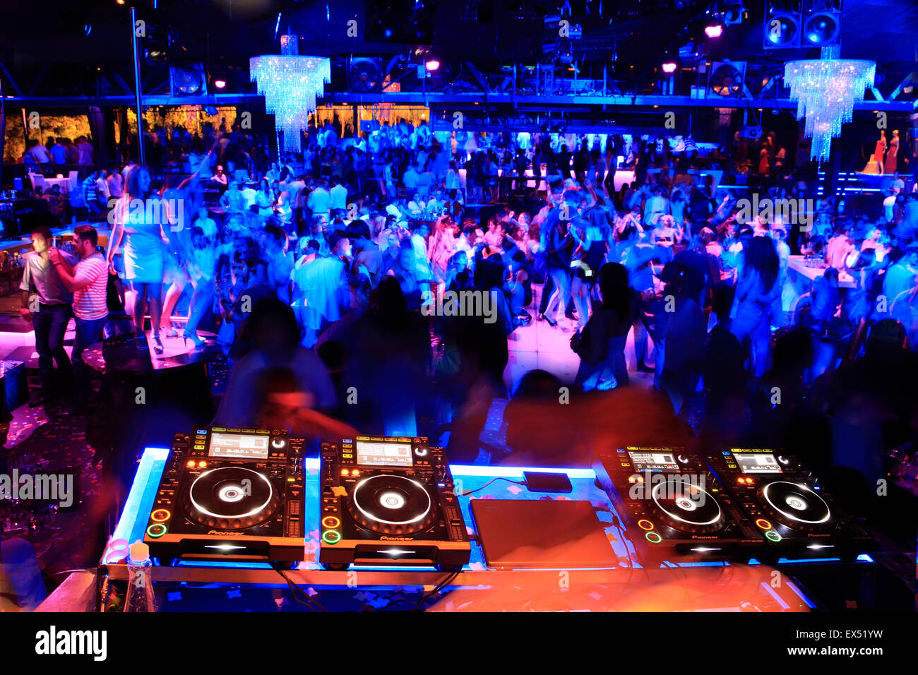 Immagine colorata di mixaggio audio deck di riproduzione di musica e jolified clubbers in background. Il nightclub di Atene, Grecia. Foto Stock