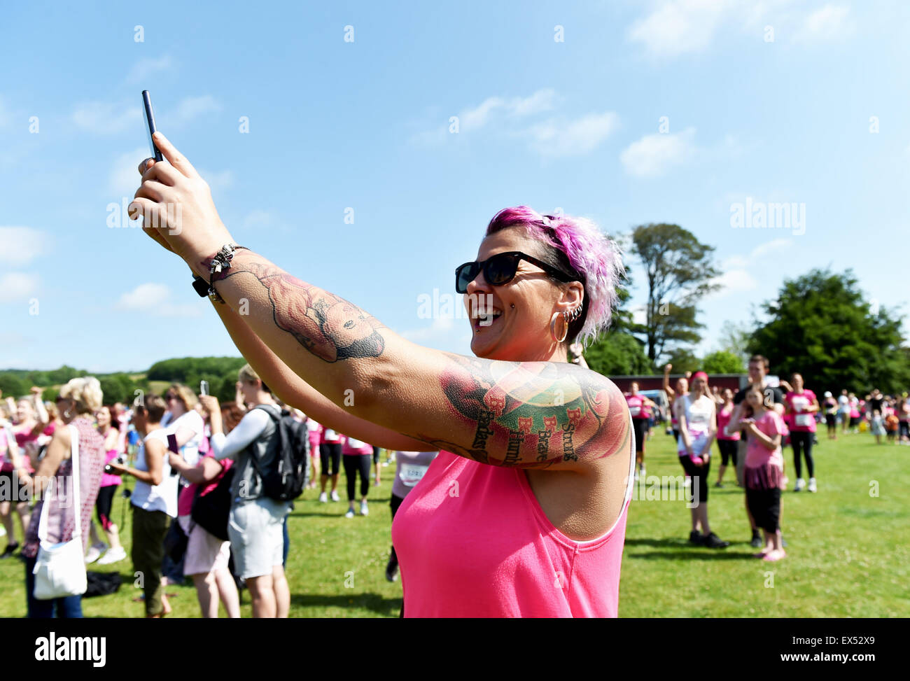Bellissima giovane donna con tatuaggi e capelli rosa stravaganti che scatta una foto di selfie all'evento CRUK Race for Life Foto Stock