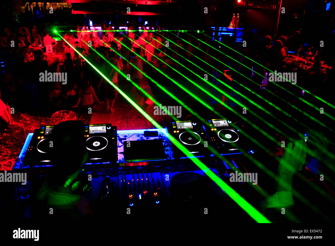 Molti Lazer / fasci laser show, Disc jockey deck e dancing clubbers in background, in un nightclub greco. Atene, Grecia. Foto Stock