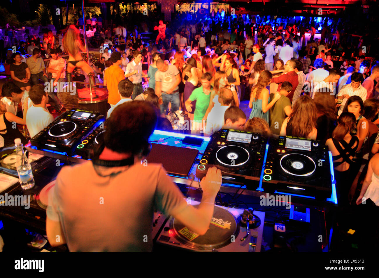 DJ sui ponti audio / dispositivi di miscelazione e dancing nightclubbers. Il nightclub di Atene, Grecia. Foto Stock