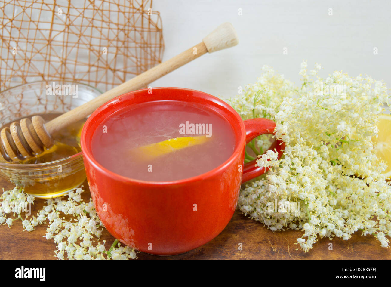 Anziano sano tè con limone servita con una ciotola di miele con un bilanciere su una tavola decorata con elderflowers Foto Stock