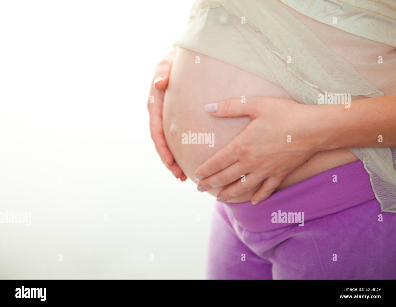 Donna incinta tenendo le sue mani a forma di cuore sul suo bambino bump. Pancia in gravidanza con le dita il simbolo del cuore. Concetto di maternità. Baby Shower Foto Stock