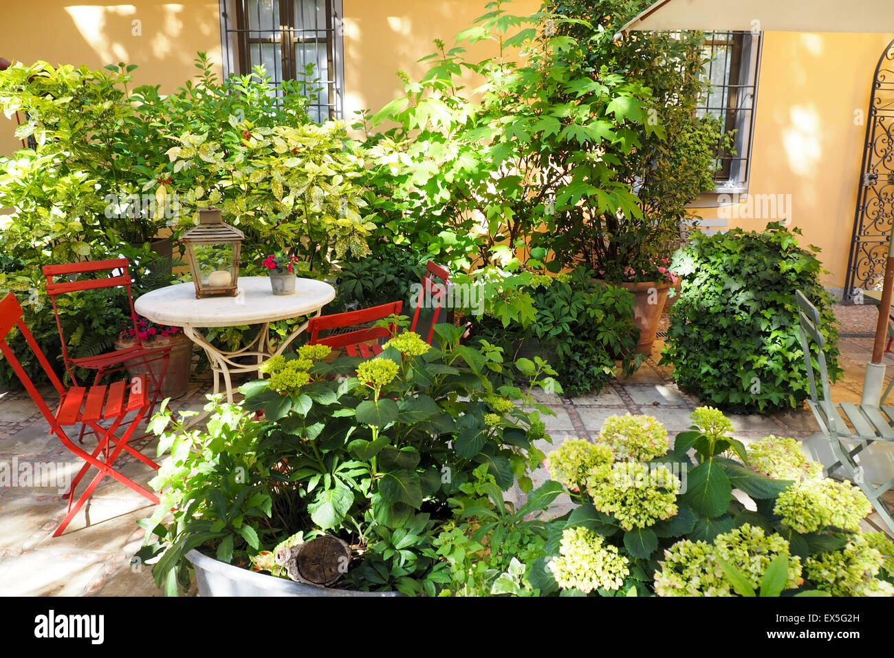 Tavolo esterno e sedie rosse in un cortile giardino Foto Stock