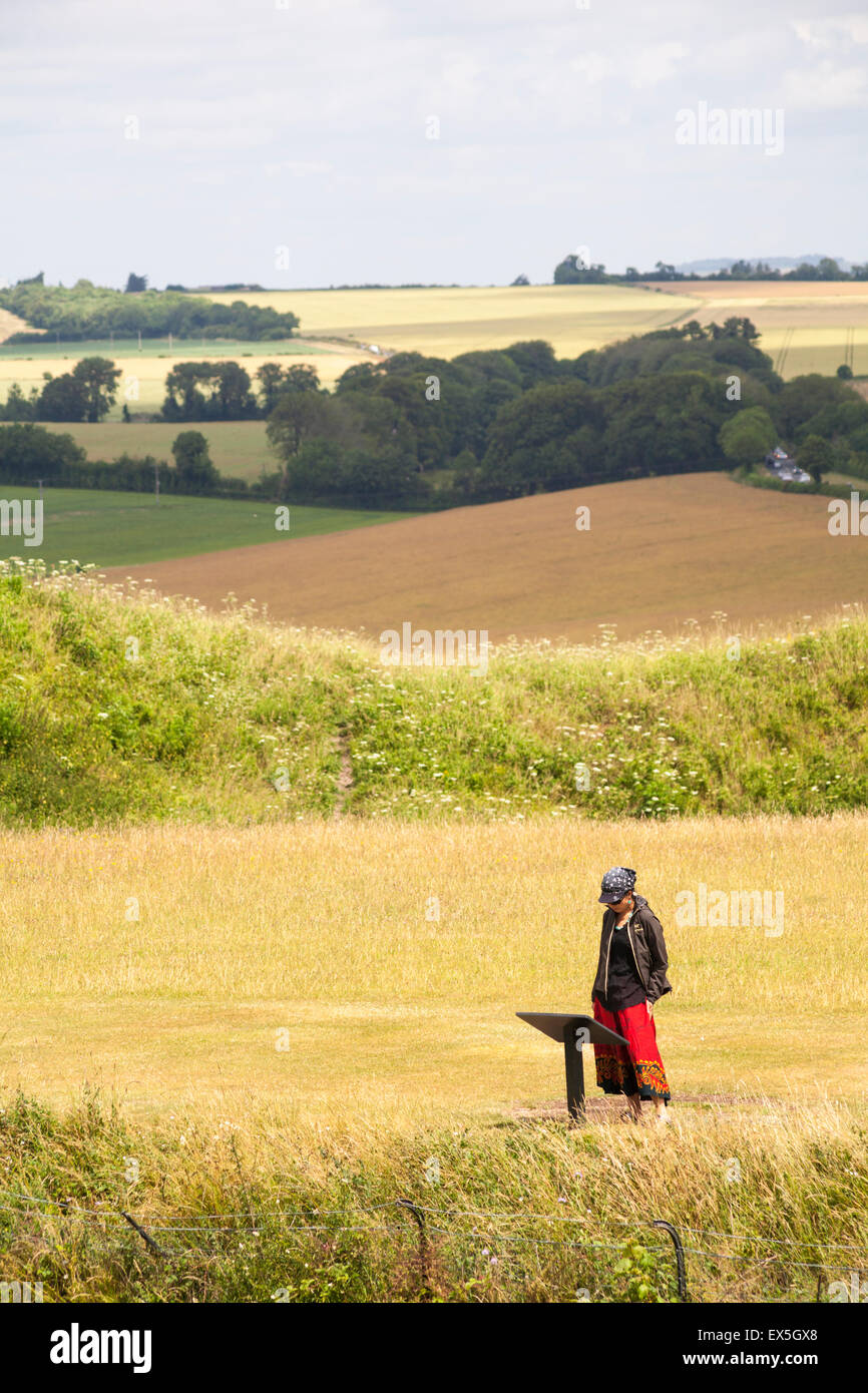 Donna che guarda un cartello informativo sul forte collinare dell'età del ferro a Old Sarum, vicino a Salisbury, Wiltshire, Regno Unito a luglio Foto Stock