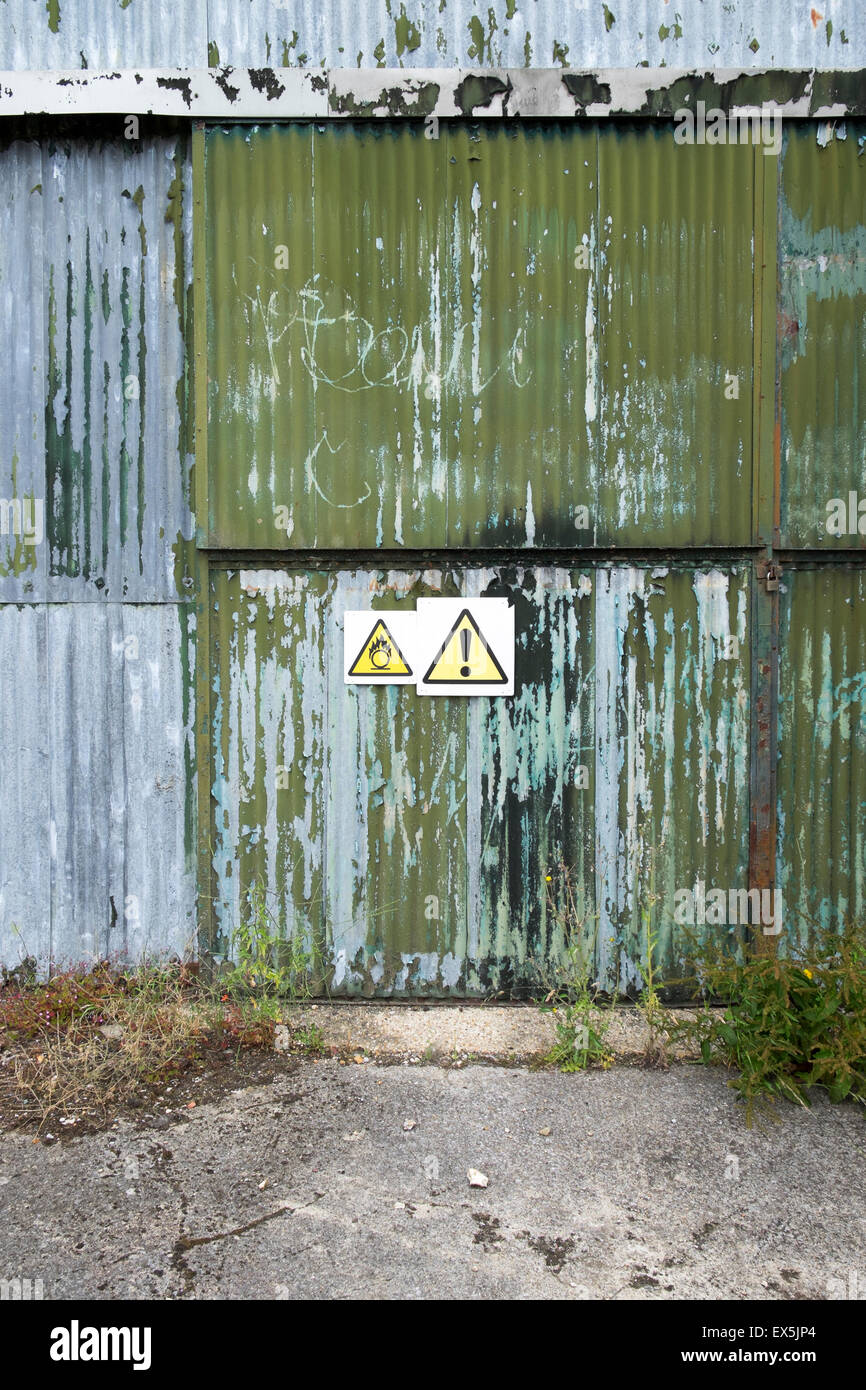 Vecchio ferro corrugato struttura con segnali di pericolo ed il distacco della vernice verde Foto Stock
