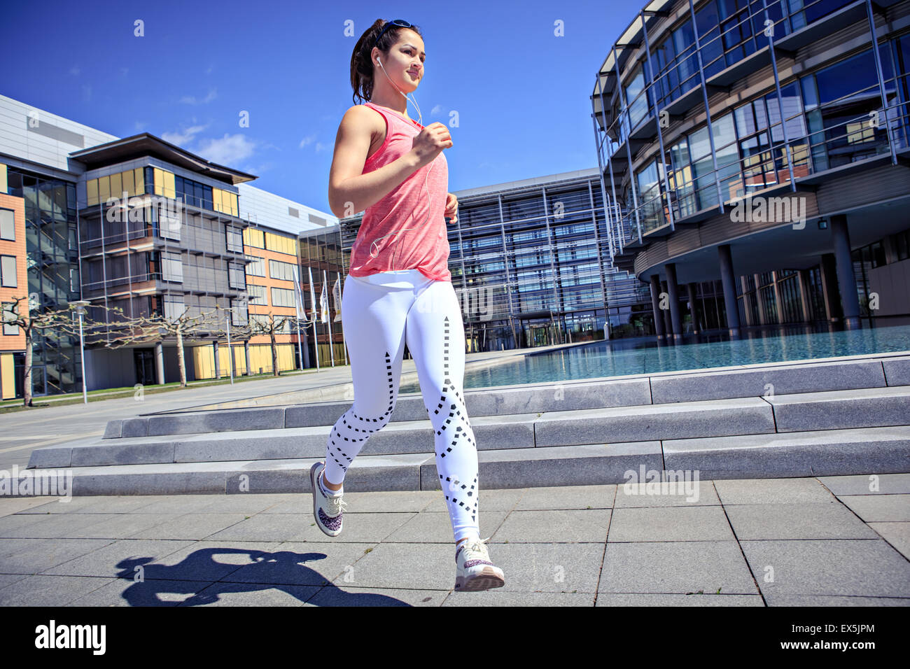 Una giovane donna jogging in città Foto Stock
