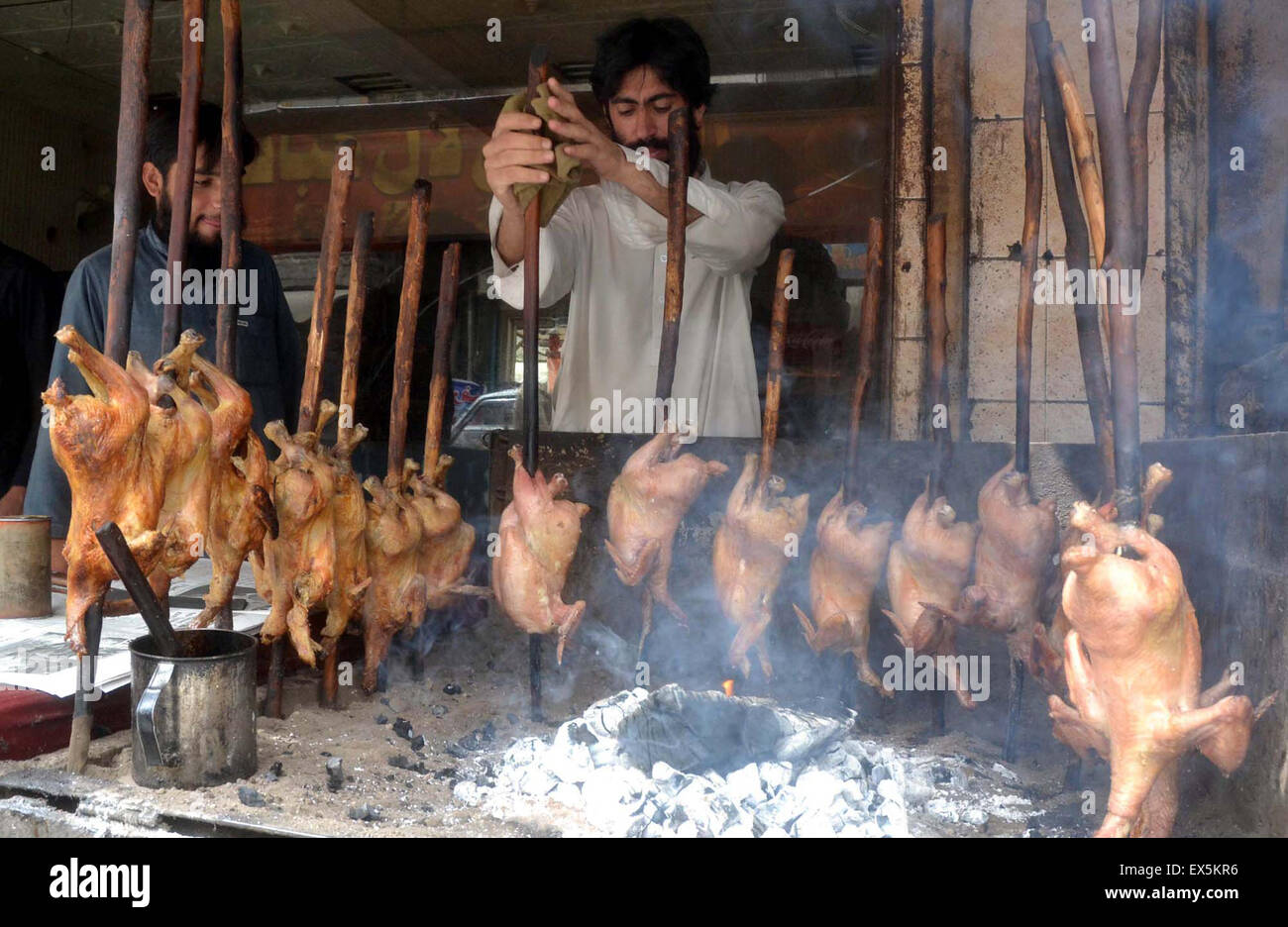 Preparazione del fornitore sajji, cibo tradizionale di vendere ai clienti prima di Iftar, al Prince Road di Quetta Martedì, luglio 07, 2015. Foto Stock