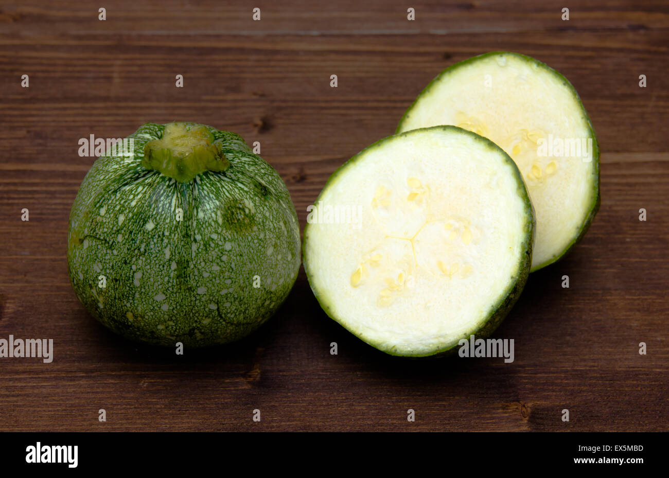 Zucchine rotonde disposte su legno scuro tabella Foto Stock