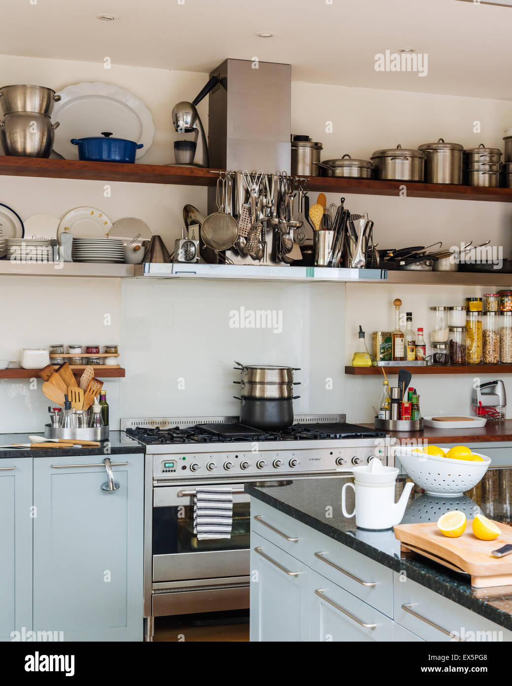 Aprire shleving in bright ariosa cucina con fornello e ripiano in granito superfici di lavoro Foto Stock