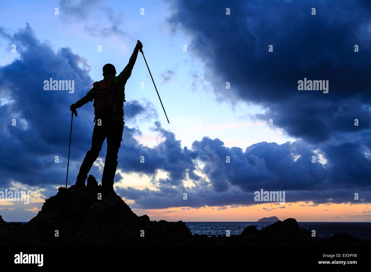 Silhouette di successo backpacker sulla parte superiore, un uomo guarda l'oceano ispiratore e isola, rilassanti o camping in montagna su mountai Foto Stock