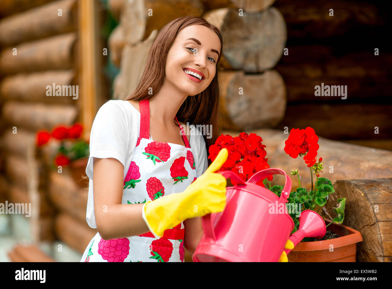 Donna di fiori di irrigazione vicino al cottage di legno Foto Stock