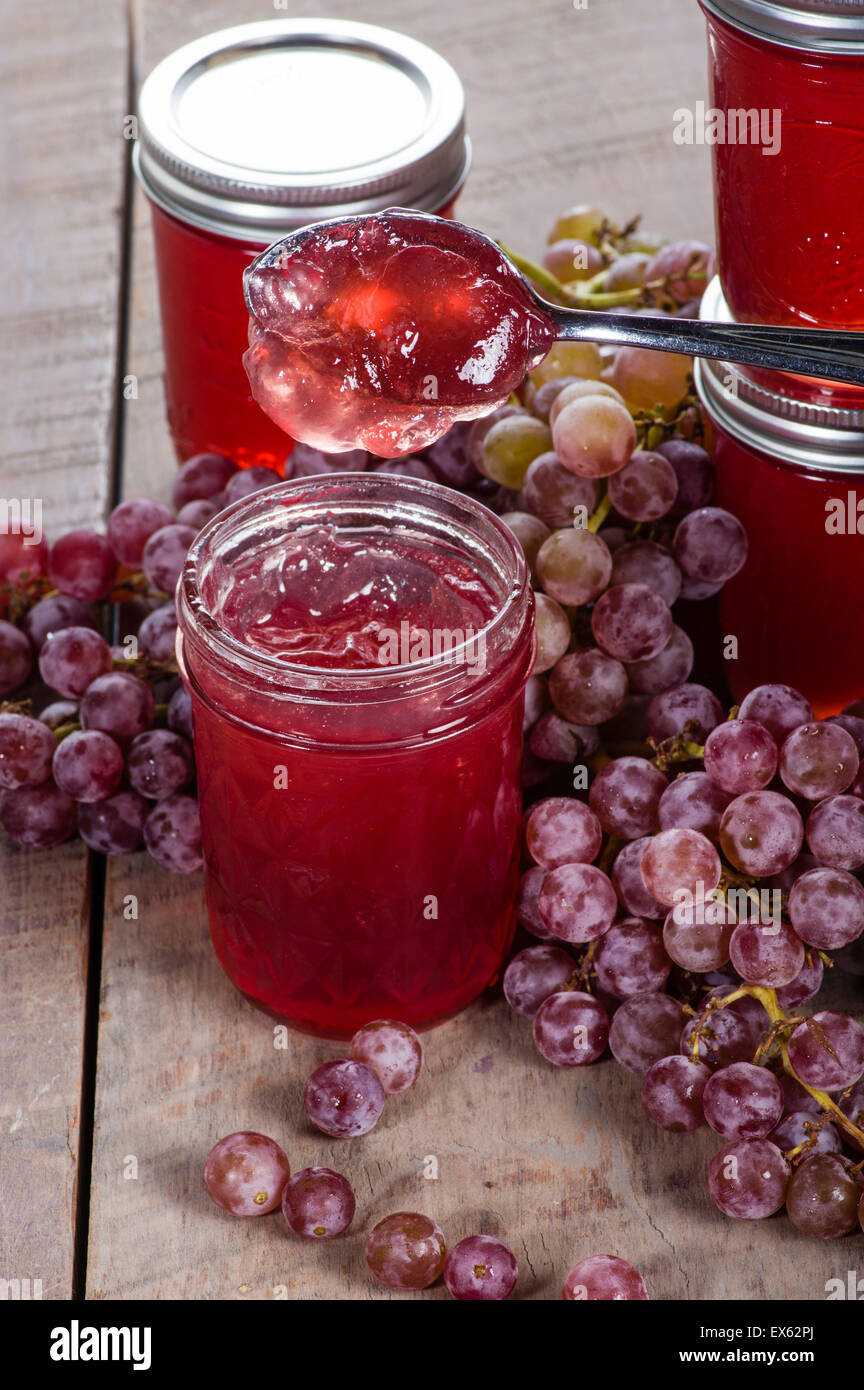Vasi di marmellata di uva con cucchiaio e jelly gocciolamento Foto Stock