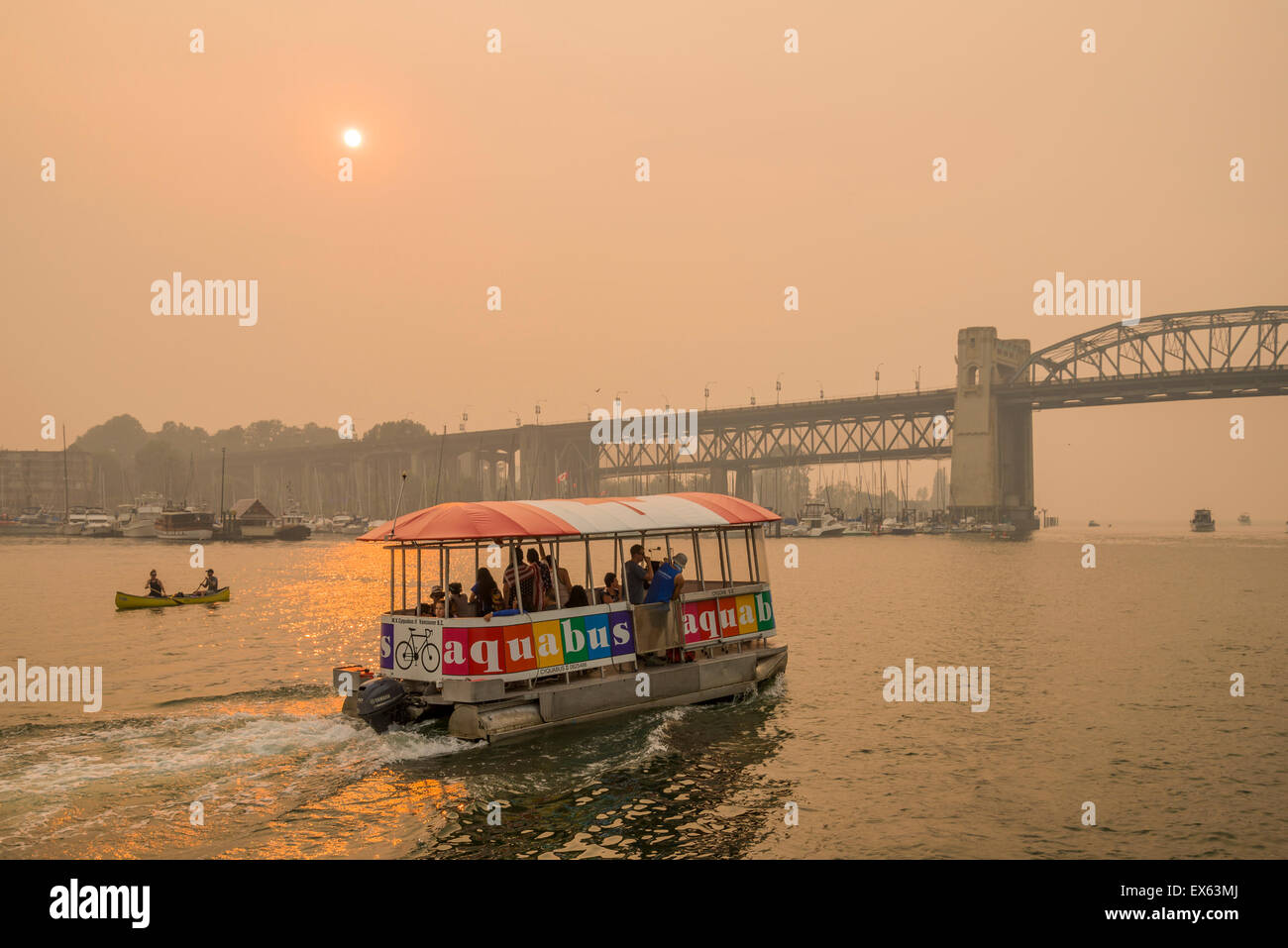 Aquabus traghetto passeggeri in False Creek, nel quadro di Forest Fire indotta smoky tramonto, Vancouver, British Columbia, Canada Foto Stock