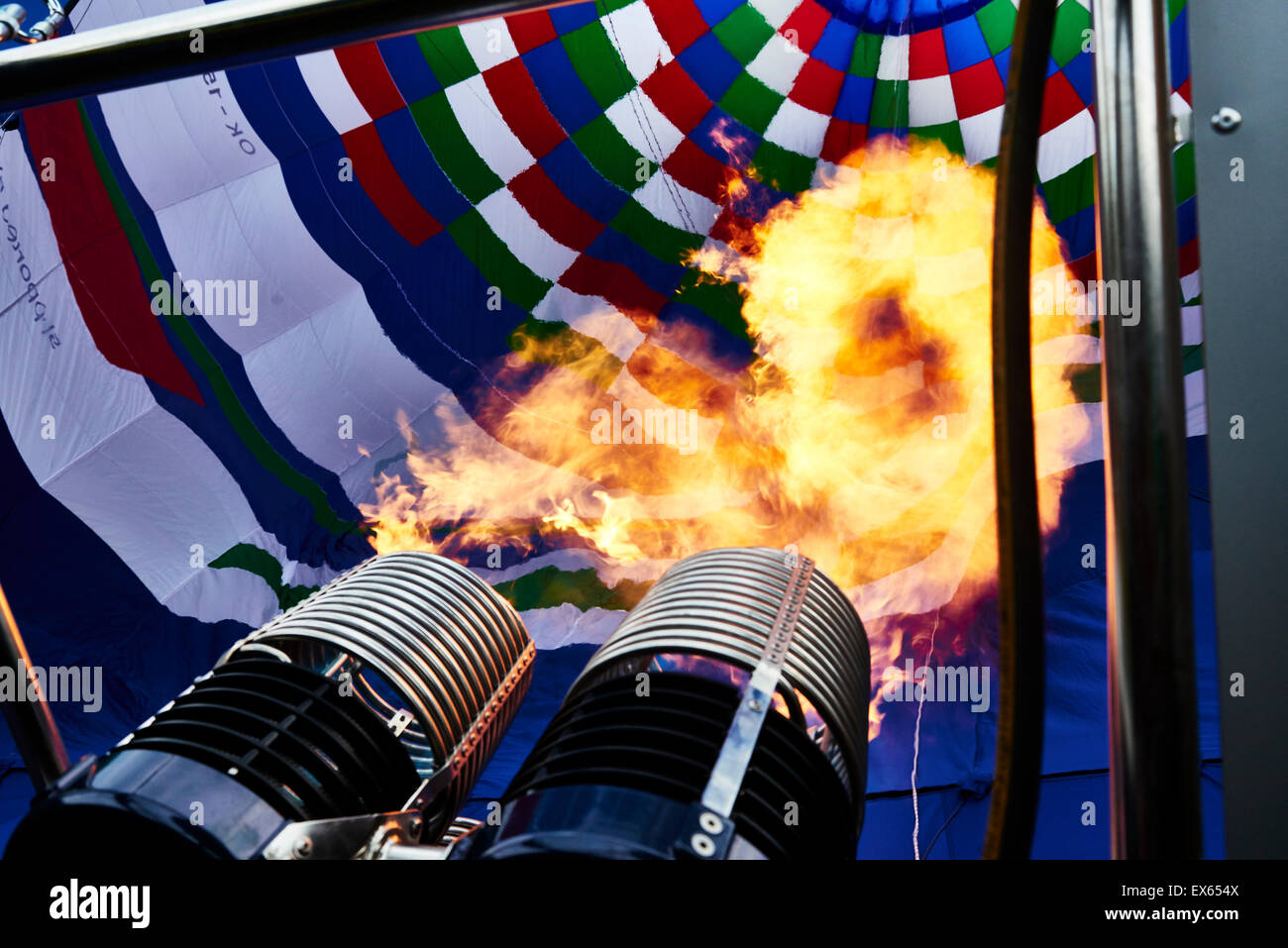 Un bruciatore con la sua super fiamma calda luce fino all'interno di una colorata mongolfiera come esso viene gonfiato per il volo Foto Stock