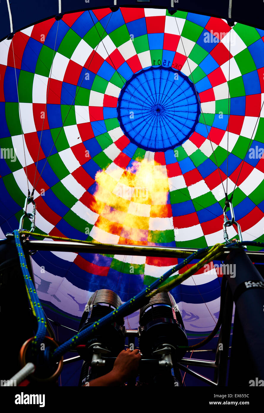 Un bruciatore con la sua super fiamma calda luce fino all'interno di una colorata mongolfiera come esso viene gonfiato per il volo Foto Stock