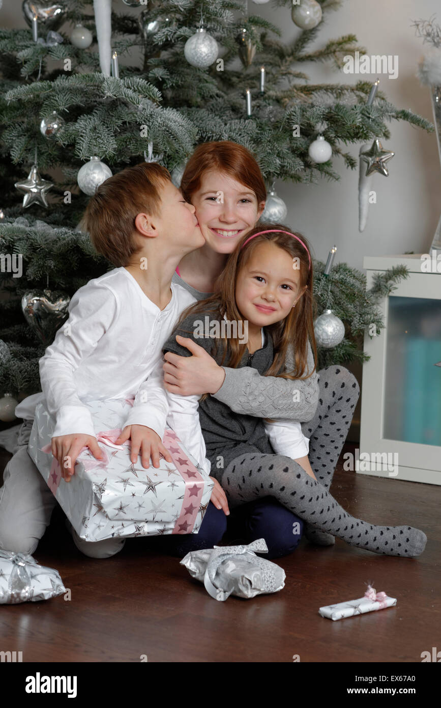 La Vigilia di Natale, felice fratelli con i regali di Natale sotto l'albero di Natale, Baviera, Germania Foto Stock
