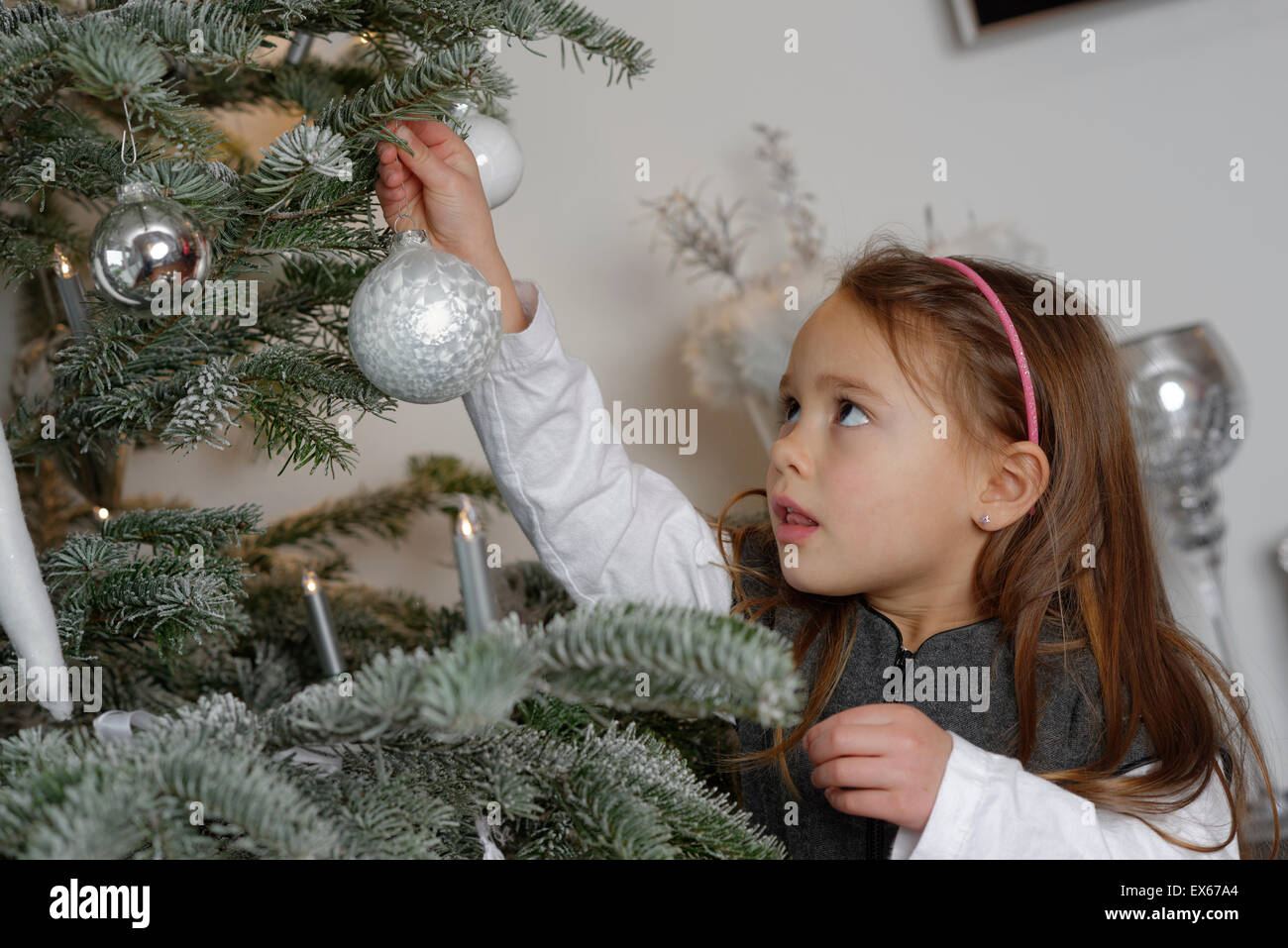 Ragazza decorare un albero di Natale con baubles, Baviera, Germania Foto Stock