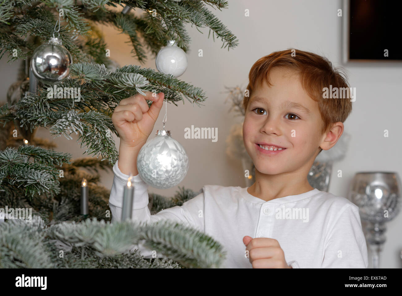 Ragazzo decorare un albero di Natale con baubles, Baviera, Germania Foto Stock