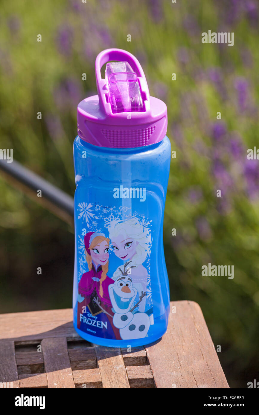 Bottiglia per bevande per bambini con personaggi Disney congelati sul tavolo con lavanda fuori fuoco dietro Foto Stock