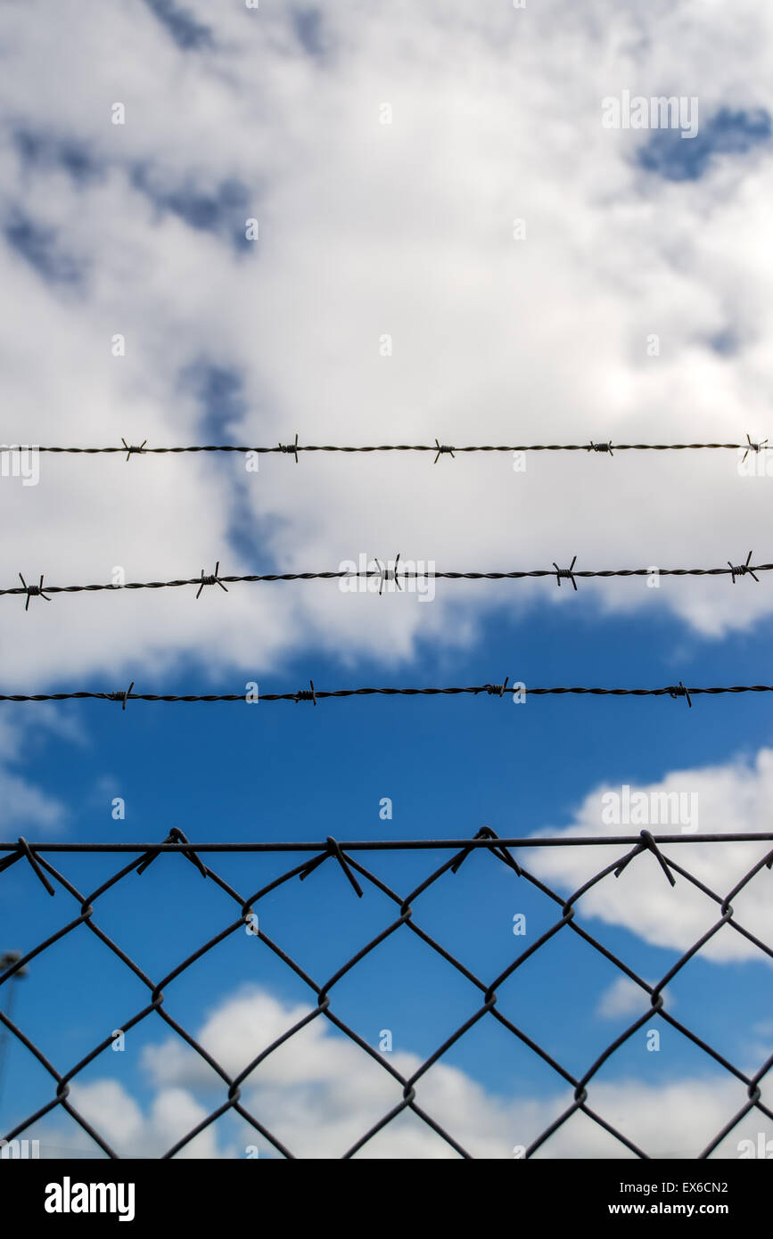 Barb recinto di filo, il bianco delle nuvole e cielo blu in background, sognando il concetto di libertà Foto Stock