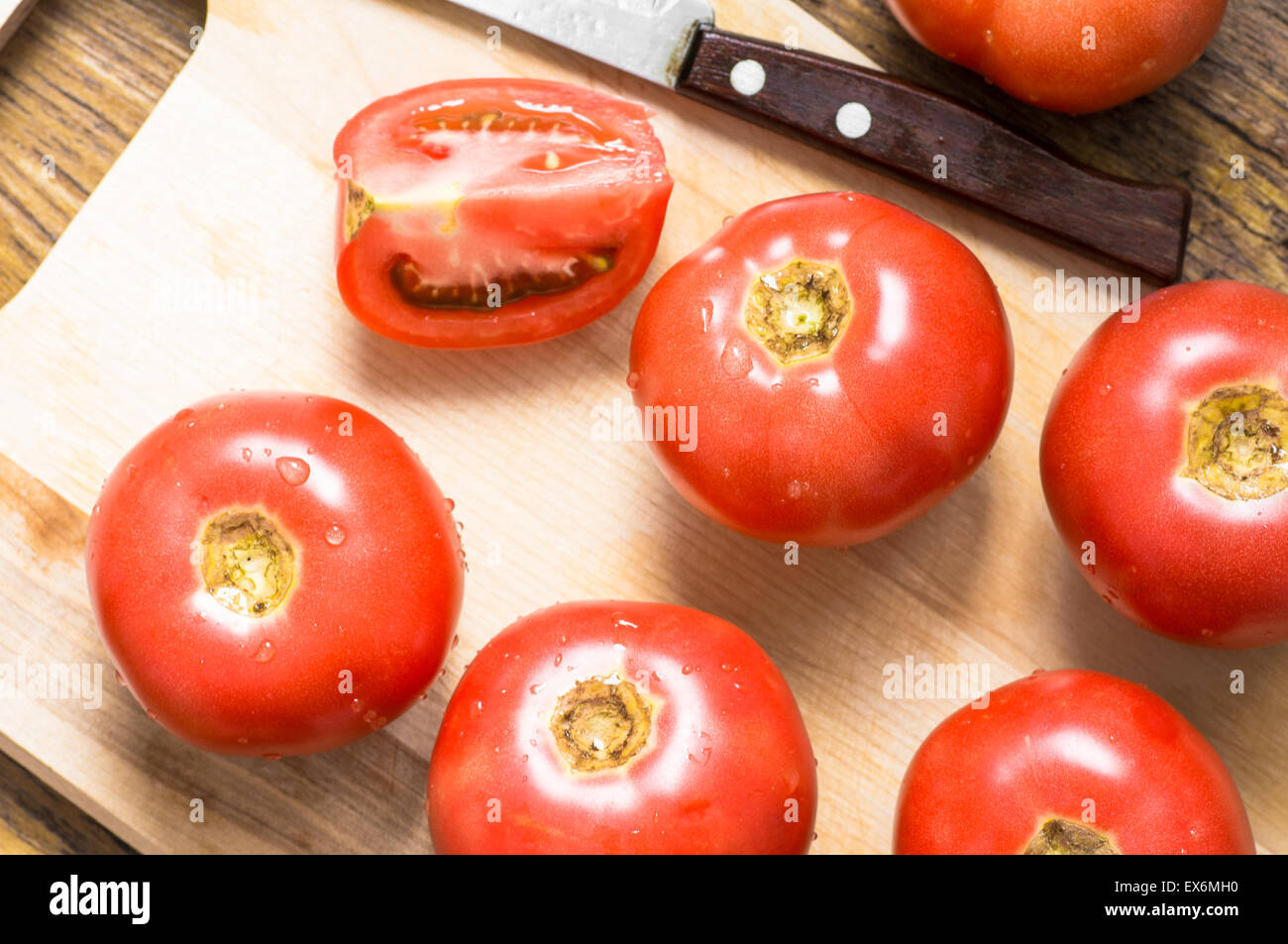 Tagliere, pomodoro intero, fetta e coltello vista superiore per lo sfondo Foto Stock