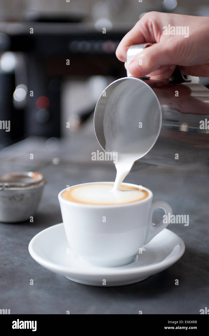 Versando cotto a vapore di latte per il cappuccino Foto Stock