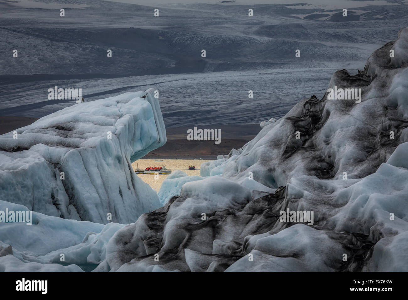 Iceberg e barca sul Jokulsarlon laguna glaciale Breidamerkurjokull, ghiacciaio Vatnajokull calotta di ghiaccio, Islanda. Foto Stock