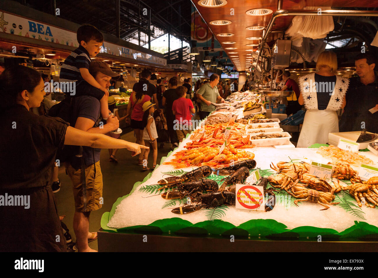 La Boqueria Barcellona - una famiglia guardando un pesce di stallo, il mercato della Boqueria, Las Ramblas, Barcelona Spagna Europa Foto Stock