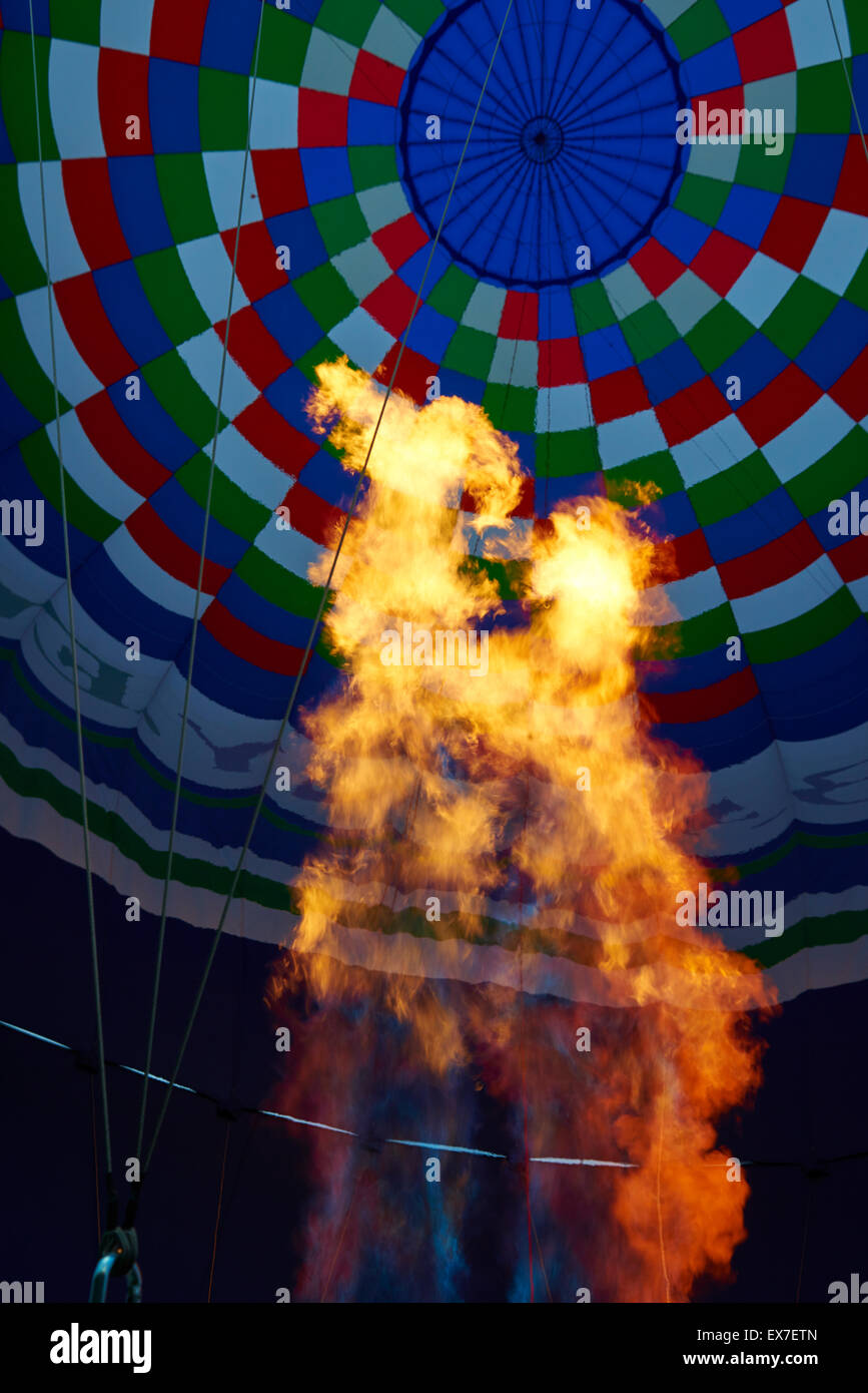 Un bruciatore con la sua super fiamma calda luce fino all'interno di una colorata mongolfiera come esso viene gonfiato per il volo Foto Stock